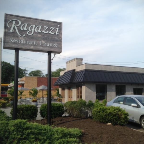 Ragazzi Restaurant Lounge sign with the building and outdoor seating area in the background.