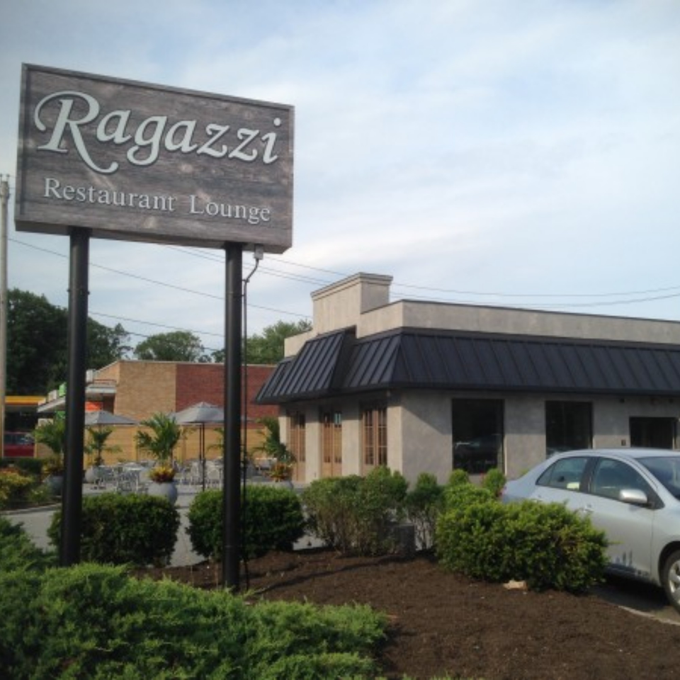 Ragazzi Restaurant Lounge sign with the building and outdoor seating area in the background.